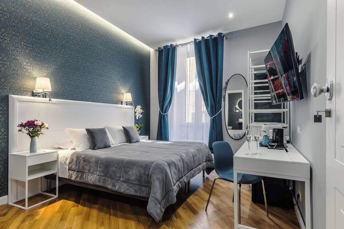 Ein modernes Schlafzimmer mit einem Bett, Nachttischen, einem Schreibtisch und einem Spiegel.