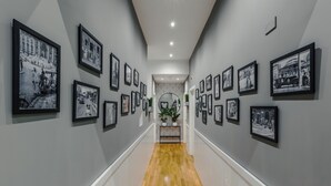 A hallway with framed black and white photographs on the walls, a wooden floor, and a white railing. - Bed and Best (Rome)