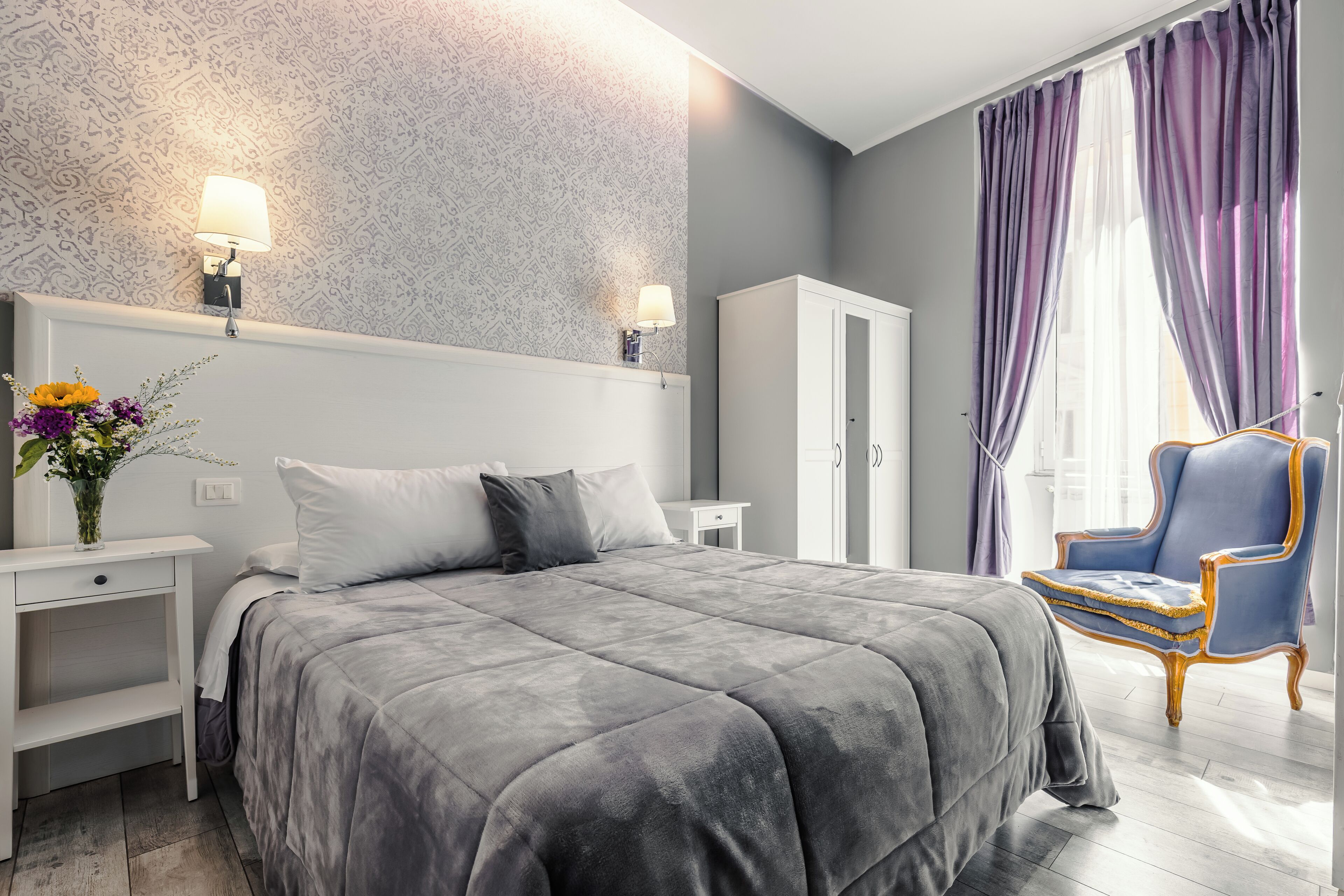A modern bedroom with a large bed, a nightstand, a dresser, and a chair.