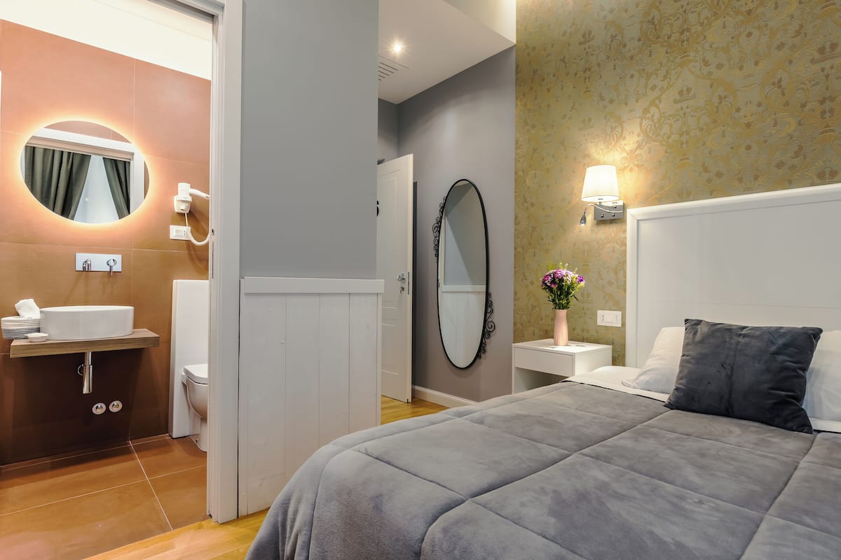 Ein Hotelzimmer mit Bett, einem Badezimmer mit Waschbecken und Toilette sowie einem Spiegel.
