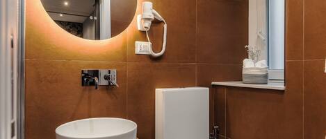 Une salle de bain moderne avec un lavabo rond, des toilettes et un miroir doté d’un éclairage intégré.