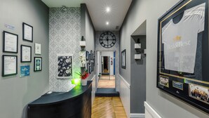 A hotel reception area with framed certificates, a clock, and a framed t-shirt on the wall. - Bed and Best (Rome)