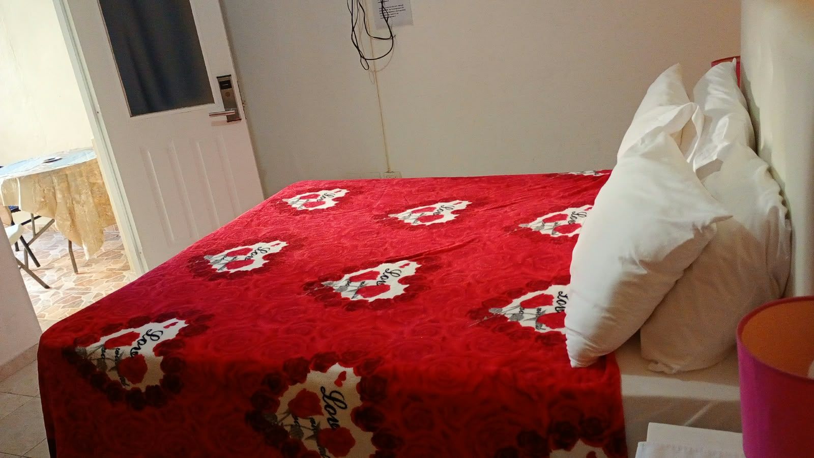 Ein Bett mit einer roten, floralen Tagesdecke und weißen Kissen.