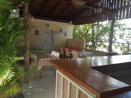 A covered outdoor seating area with a bar, tables, and chairs.