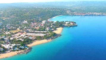 An aerial view of a coastal resort with beachfront properties, a pier, and a large body of water.