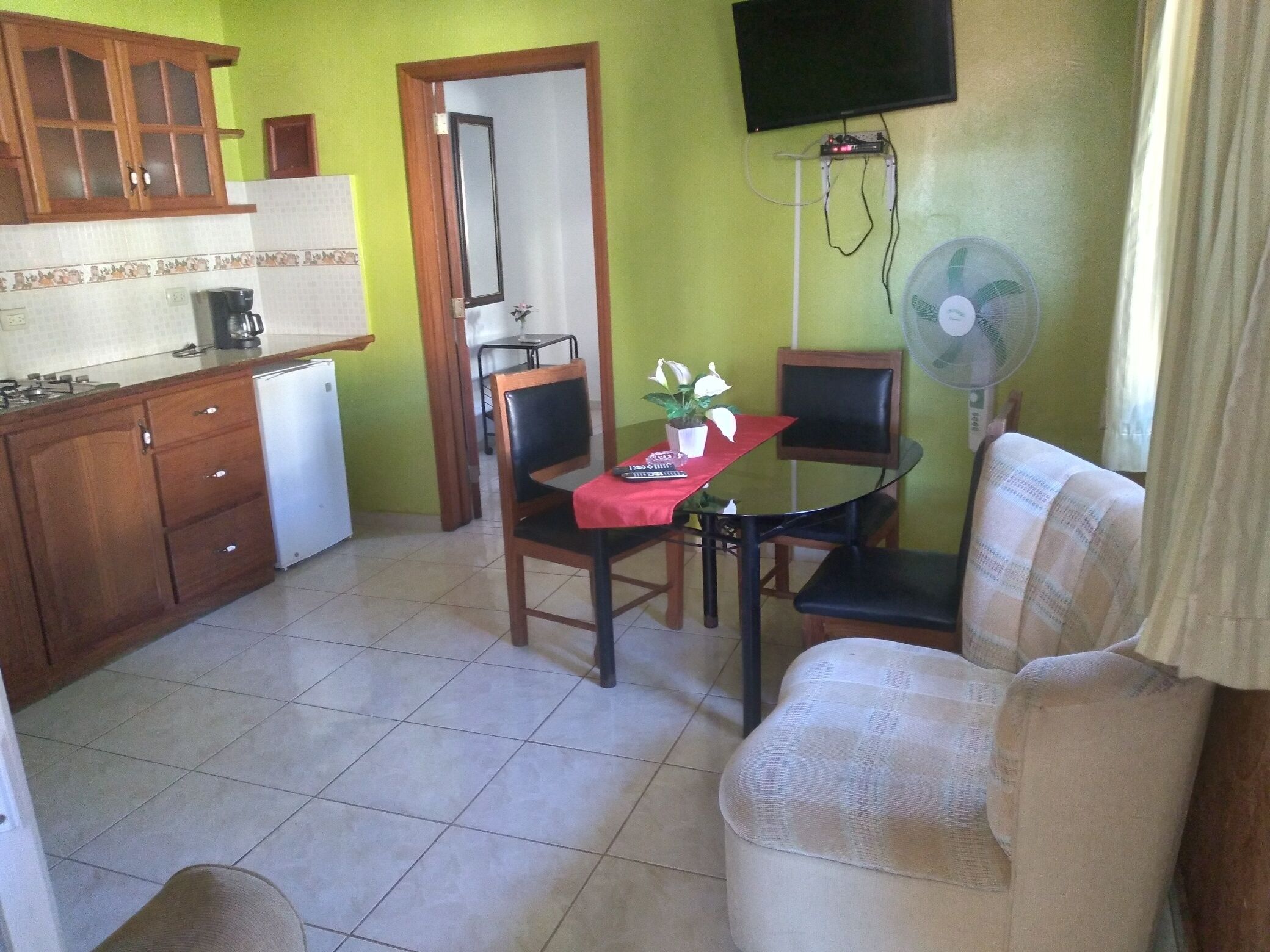 A compact kitchen with wooden cabinets, a white refrigerator, and a dining area with a table and chairs.