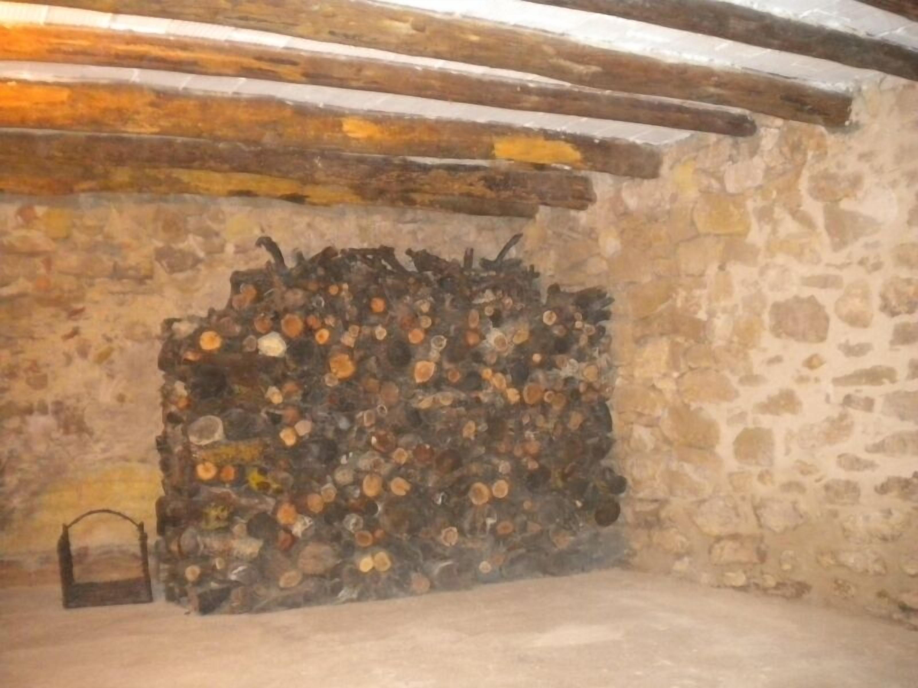 Un muro de piedra rústico con una pila de leña.