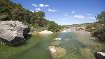 Une rivière aux eaux claires, bordée de rochers et d’arbres.