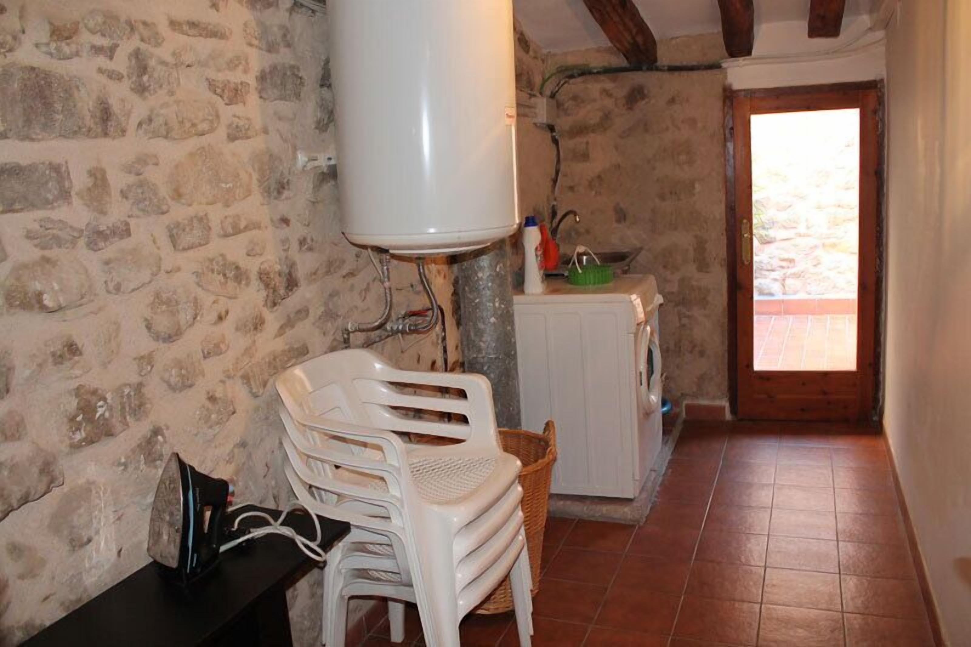 Una estança rústica amb parets de pedra, un radiador blanc, una porta de fusta i un sòl de rajola.