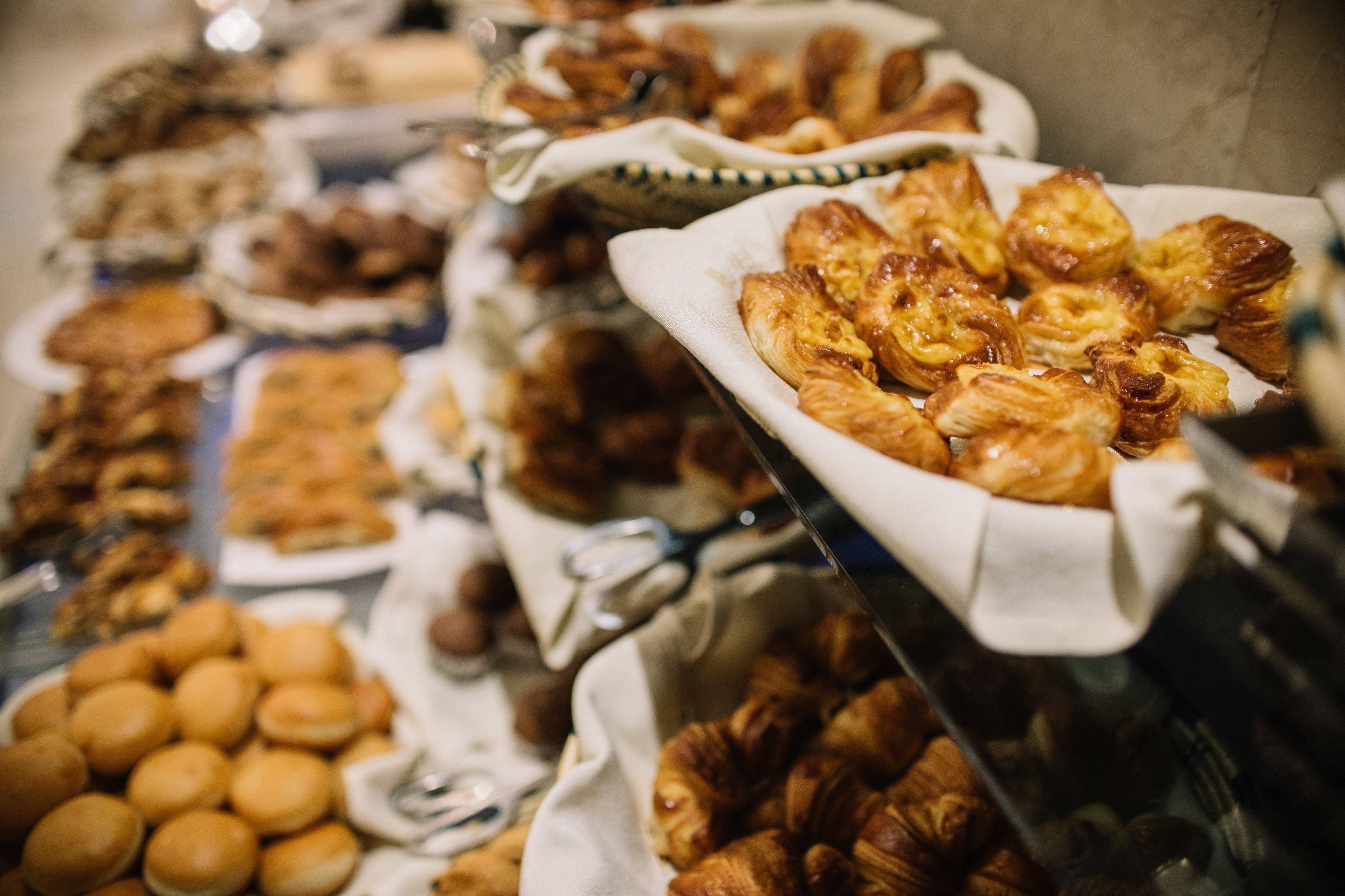 A buffet with various baked goods including pastries and bread.