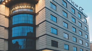 Un hôtel à plusieurs étages, reconnaissable à son grand panneau « Golden Tulip », à ses larges fenêtres et à son hall d’entrée bien éclairé.