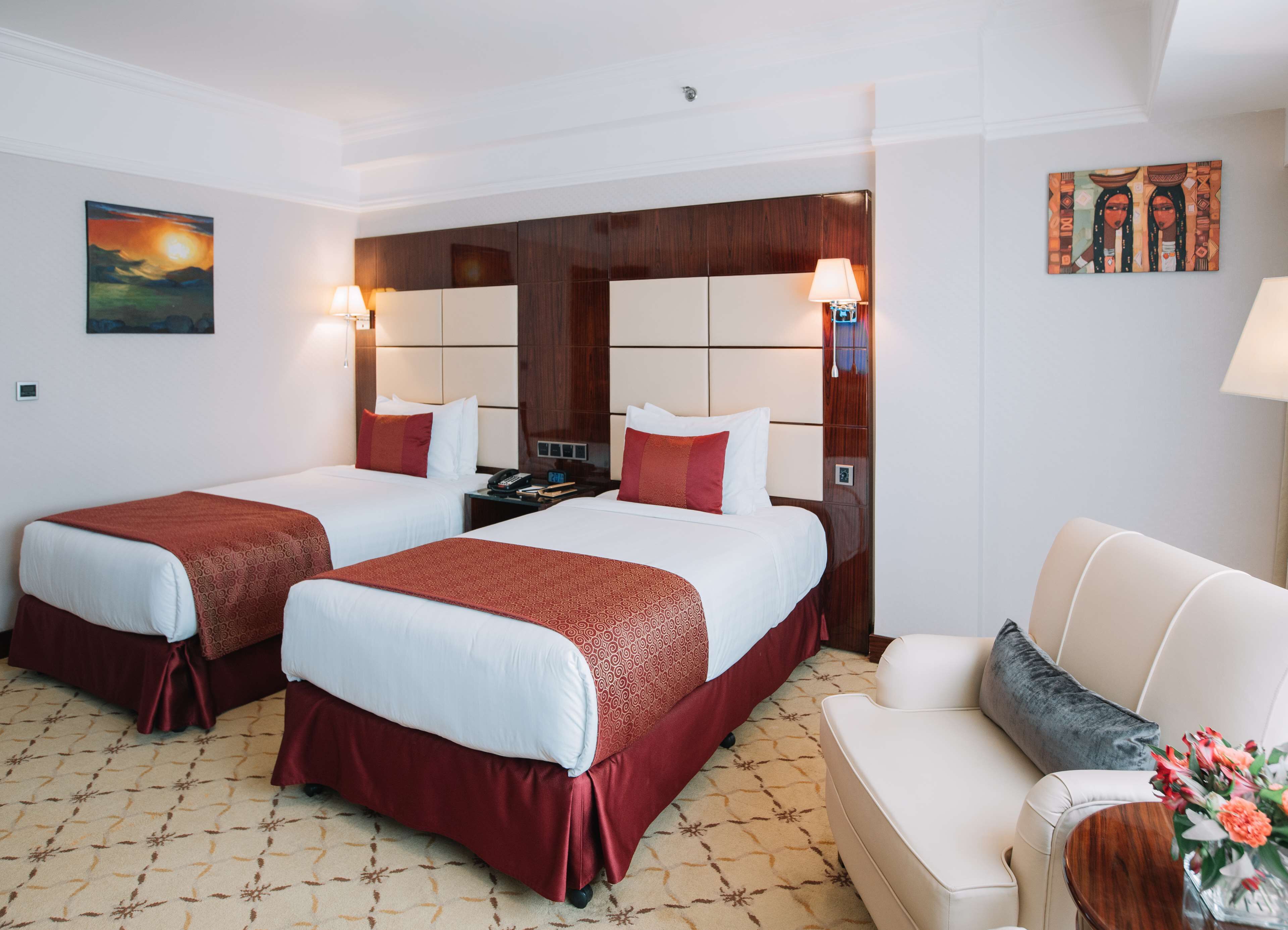 Une chambre d’hôtel avec deux lits, un canapé, une table de chevet et un tableau au mur.