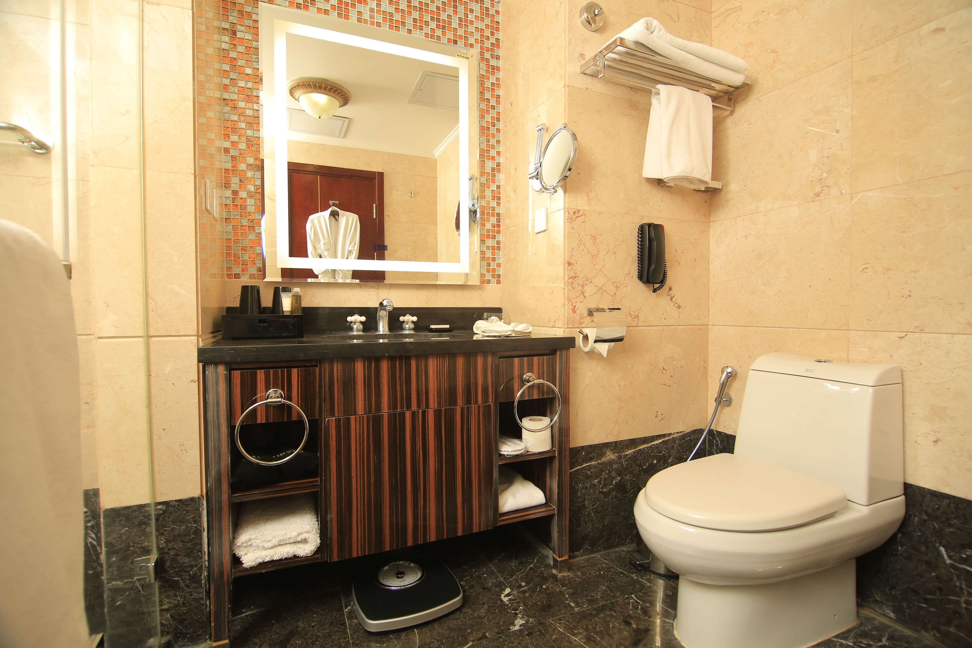 A bathroom with a marble sink, a toilet, a scale, and a mirror.