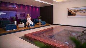 Relax by the rectangular pool surrounded by seating areas with comfortable chairs and a small table.