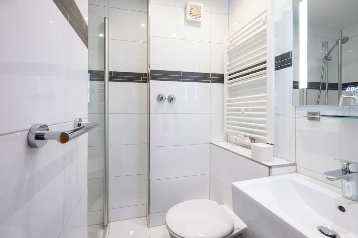 Een moderne badkamer met een glazen douchecabine, een wit toilet en een wastafel met spiegel.