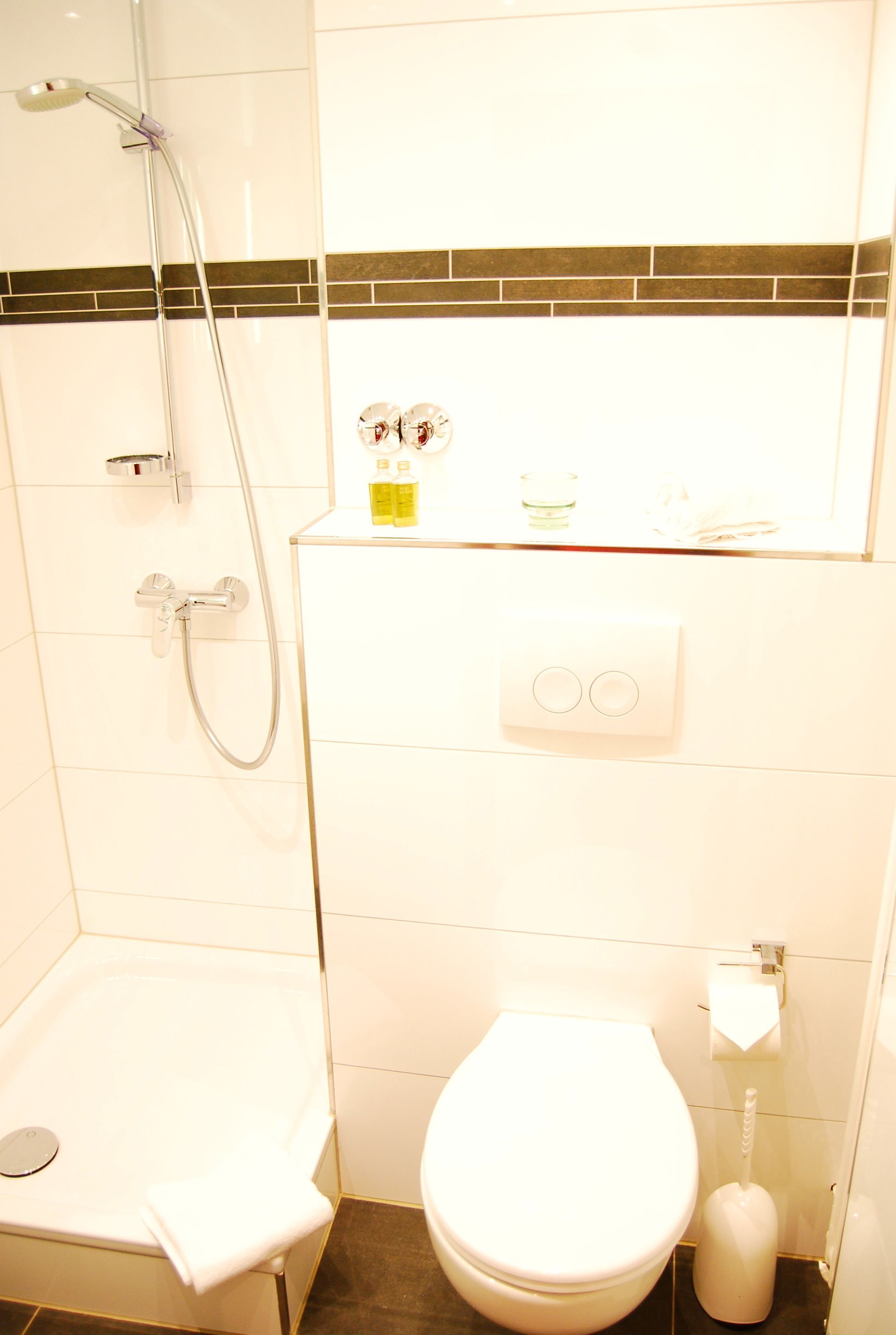 A bathroom with a shower, toilet, and a small sink.