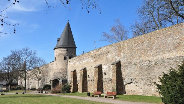 Un bâtiment historique en pierre, doté d’une tour, d’un chemin pavé et de bancs.