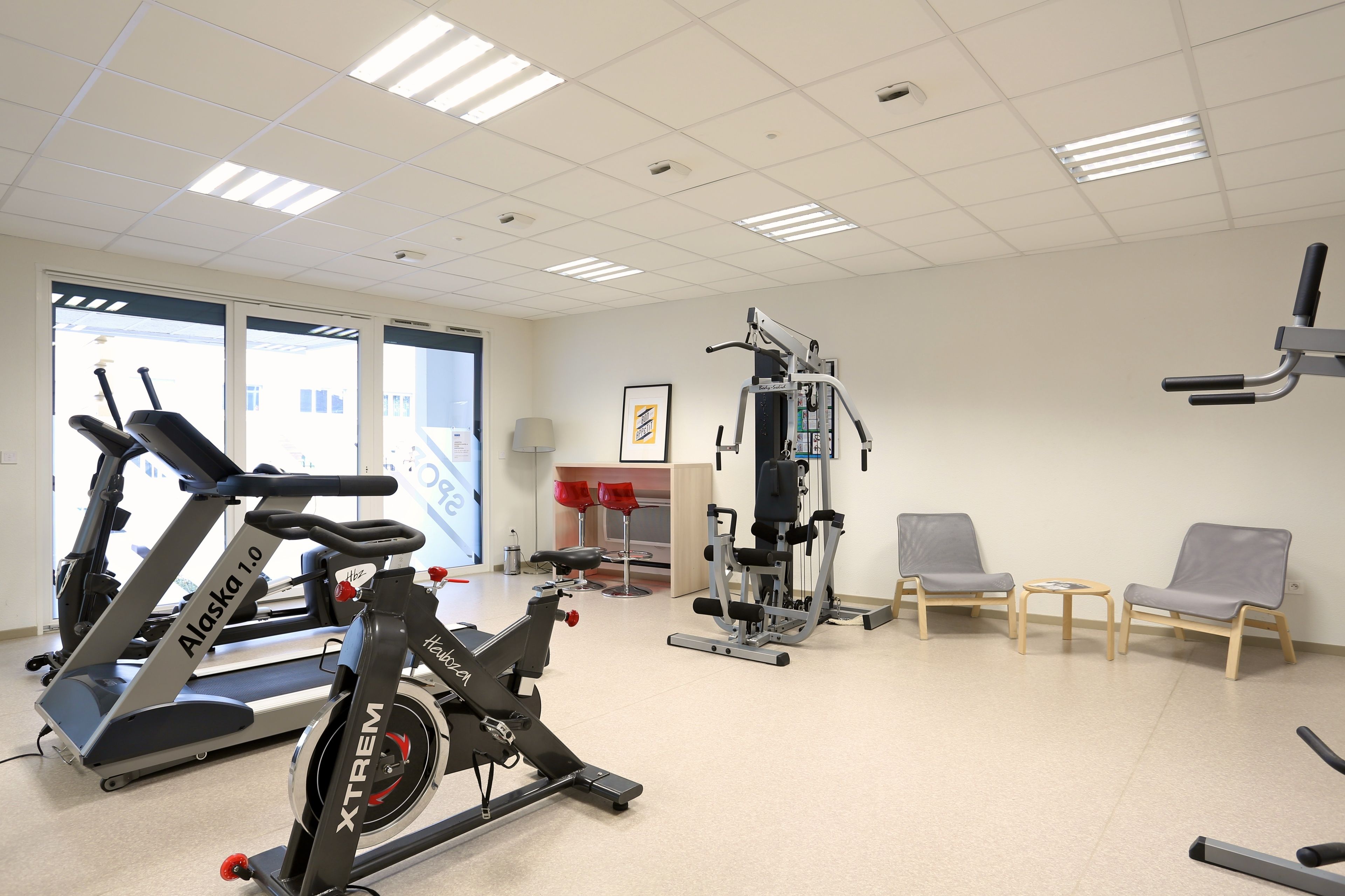 A gym with cardio machines, weightlifting equipment, and seating areas.