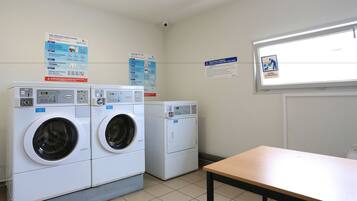 A laundry room with two front-loading washing machines, a table, and informational posters on the walls.