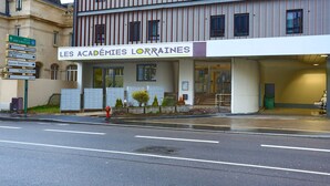 A building with a sign reading "LES ACADEMIES LORRAINES" and directional signs for nearby locations. - Apparteo Nancy (Nancy)