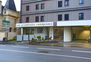 Un edificio con un cartel que dice "LES ACADEMIES LORRAINES" y señales que indican la dirección a lugares cercanos.