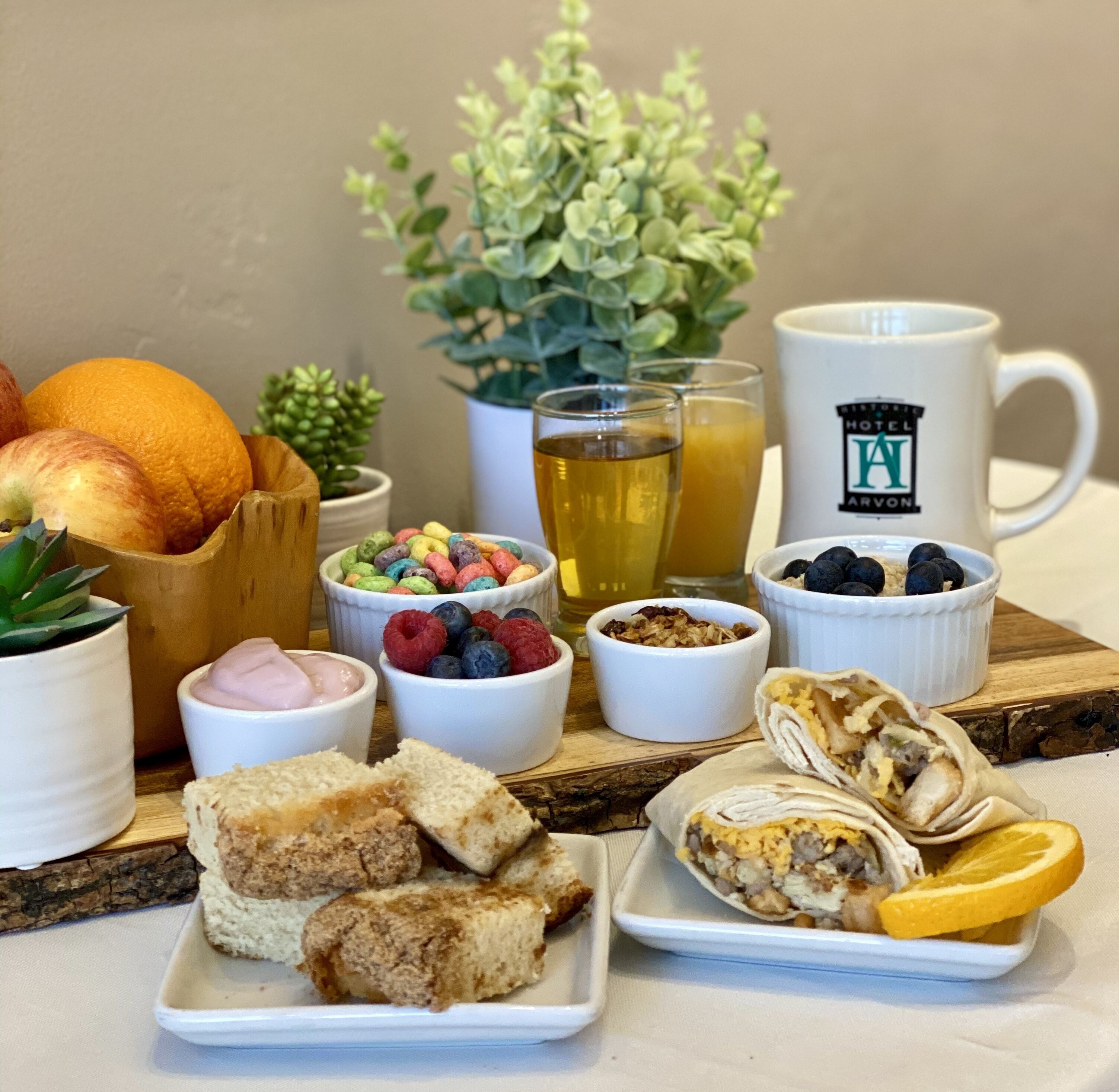 A breakfast setting with various food items, including fruits, cereal, and pastries, arranged on a wooden board.