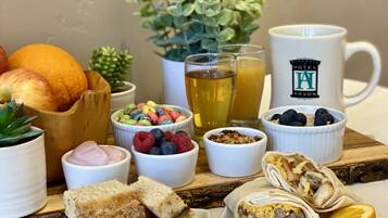 Un desayuno con diversas opciones de comida, como frutas, cereales y pasteles, dispuesto sobre una tabla de madera.