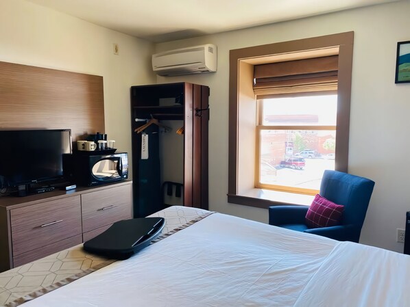 Habitación de hotel con cama, televisión, armario, ventana con vistas y aire acondicionado.