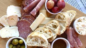 A charcuterie board with various meats, cheeses, olives, grapes, and bread.