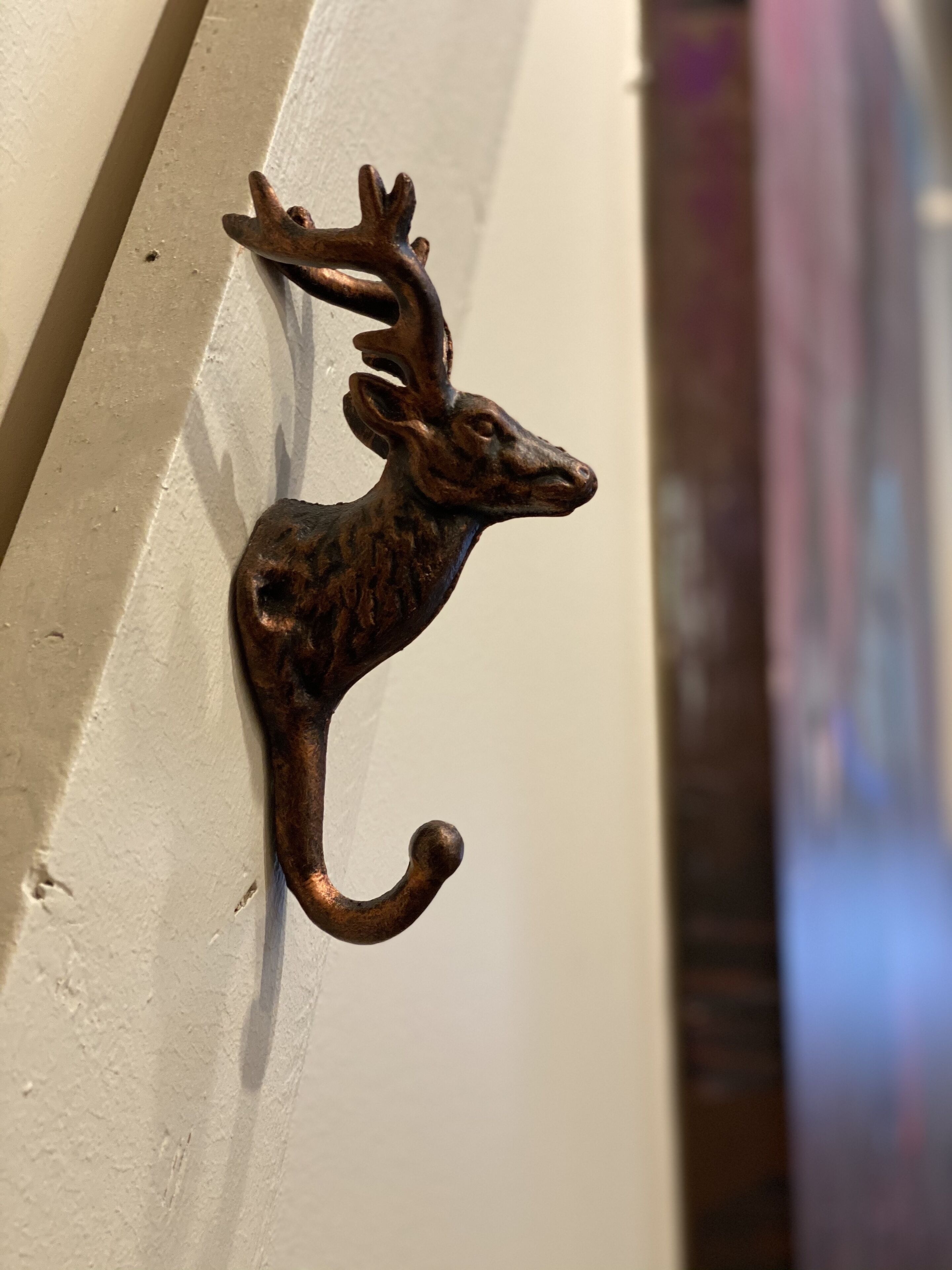 A metal deer-shaped door knocker mounted on a white door.