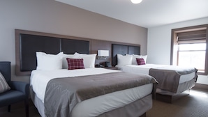 Habitación de hotel con dos camas, un escritorio, una silla y una ventana con persianas.