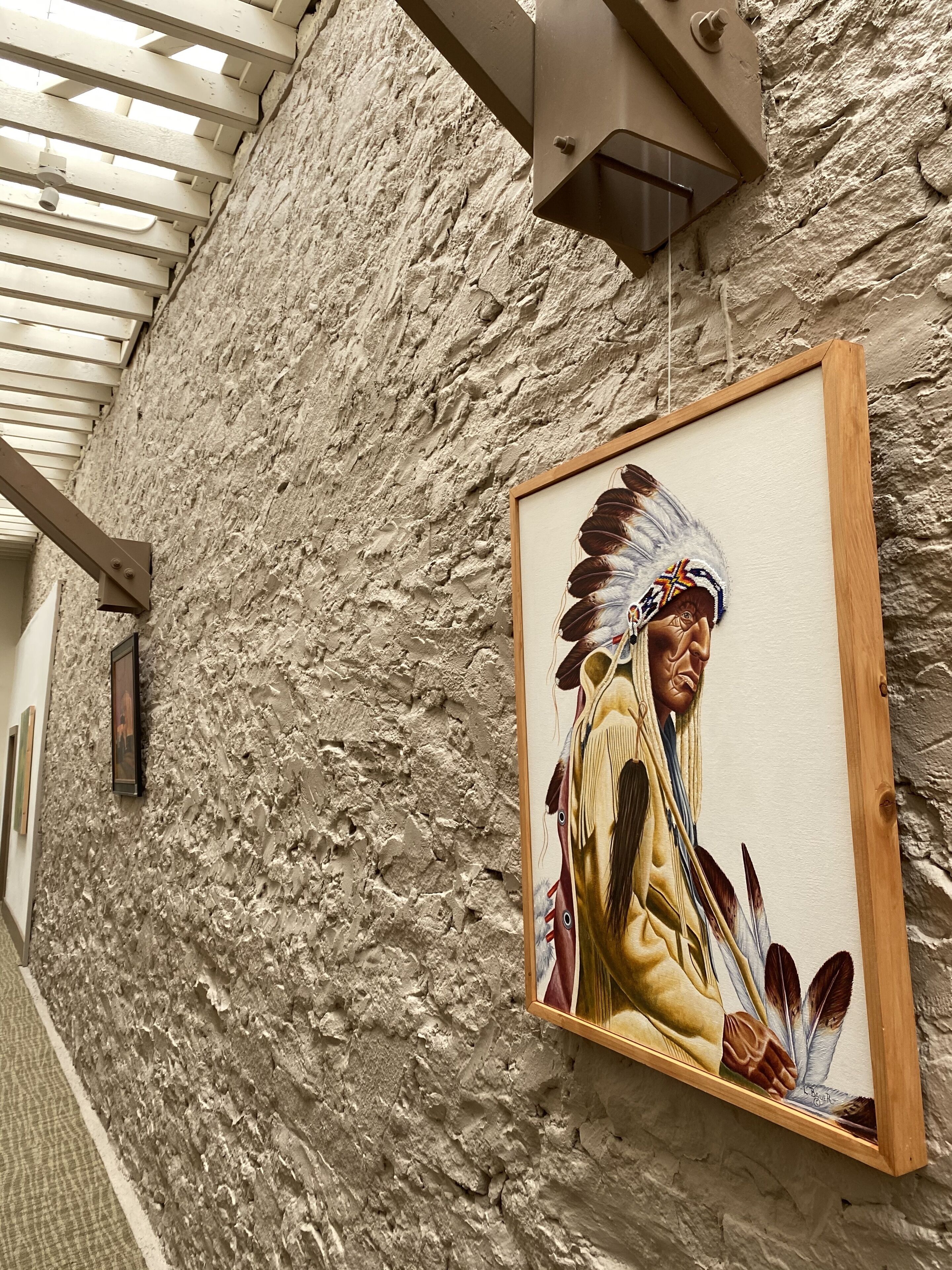 Una pared texturizada con un cuadro enmarcado que muestra una figura nativa americana.
