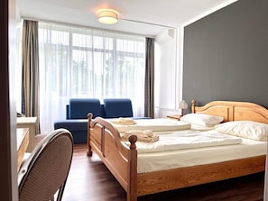 Una habitación de hotel con una cama de madera, un escritorio y una silla.