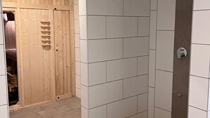 Un espace douche avec des carreaux blancs et une porte en bois.