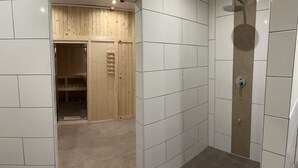 Une salle de bain moderne avec un sauna en bois, des murs carrelés et un espace douche.