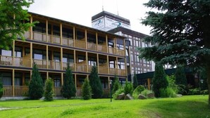 Un immeuble à plusieurs étages doté de balcons, entouré de verdure et d’arbres.