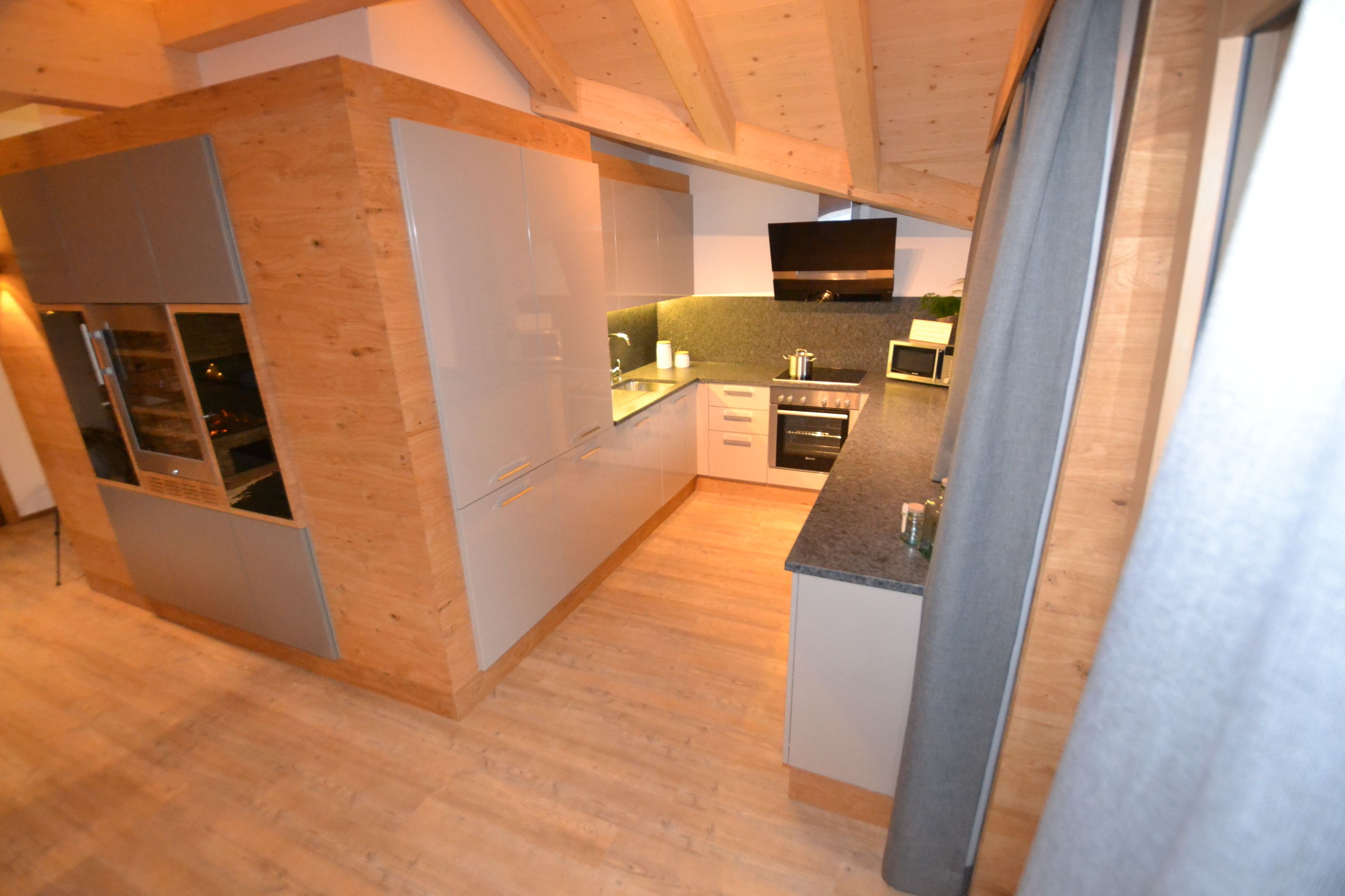 Eine moderne Küche mit Holzschränken, einem eingebauten Ofen und einer Edelstahlspüle.