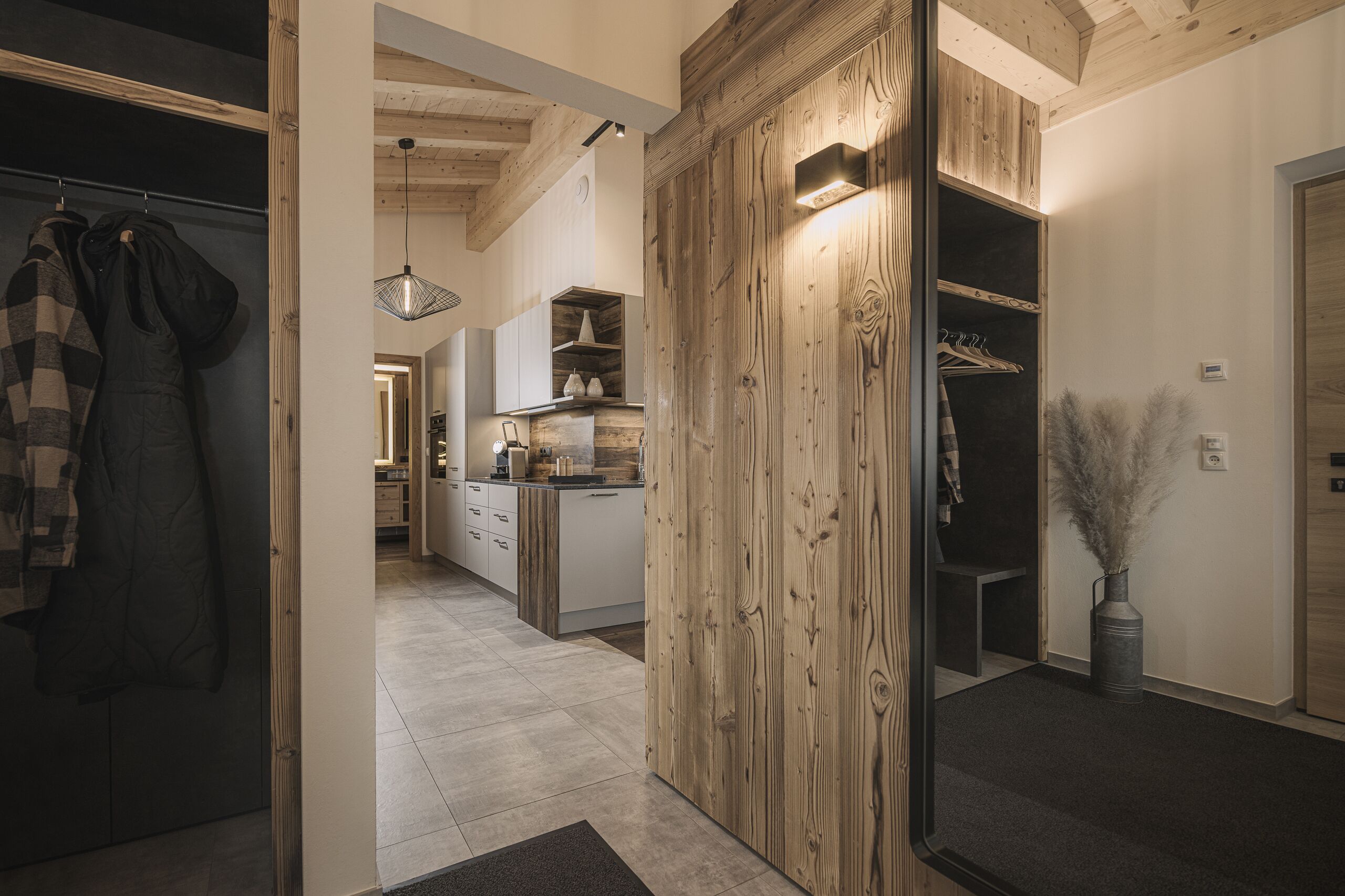 Una cocina moderna con detalles de madera, un comedor y un pasillo que lleva a un dormitorio.