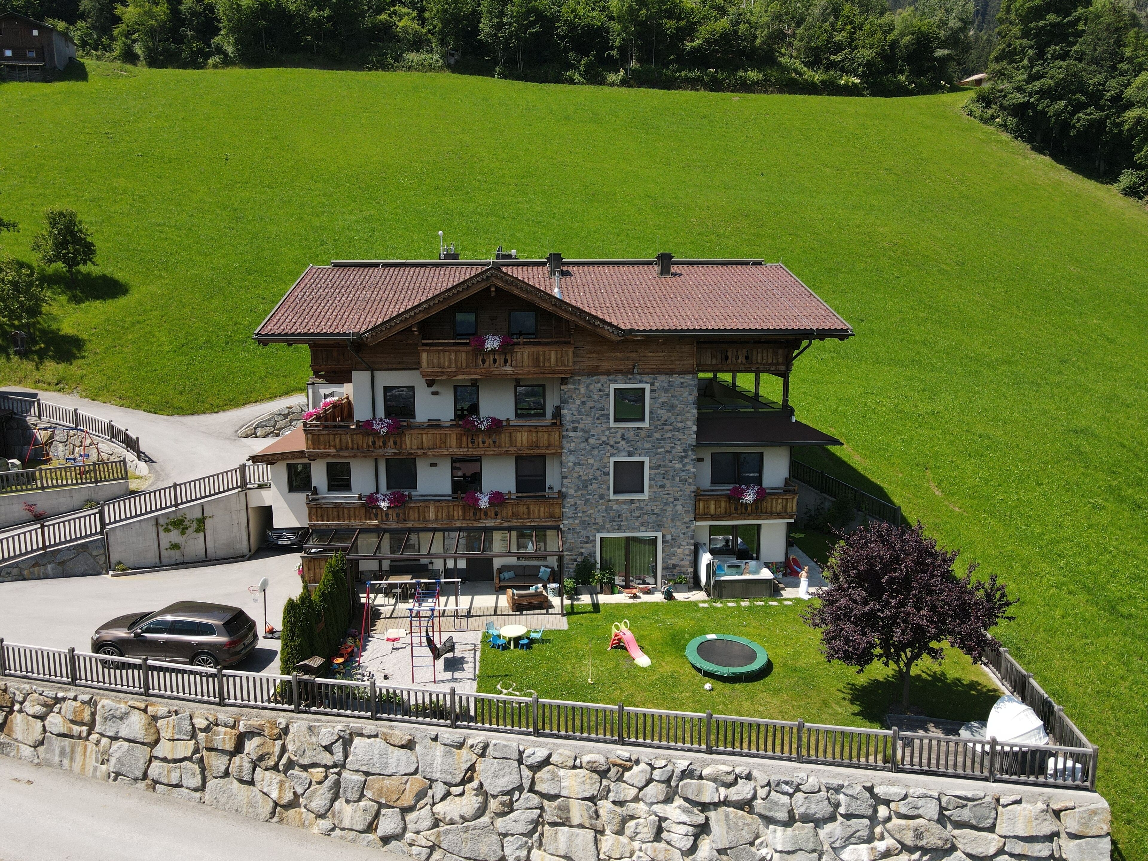 A multi-story building with balconies, a stone facade, and a well-maintained lawn.