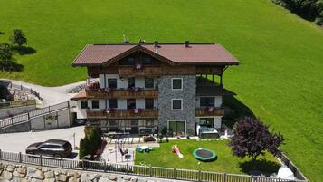 A multi-story building with balconies, a stone facade, and a well-maintained lawn.