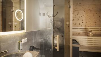 Un baño moderno con cabina de ducha de vidrio, sauna de madera y espejo con luz.