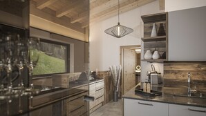 Une cuisine moderne avec des meubles en bois, un pare-feu en verre et un luminaire suspendu.