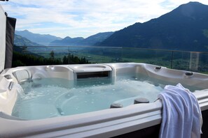 Een hottub met een handdoek erin, met uitzicht op een bergachtig landschap.