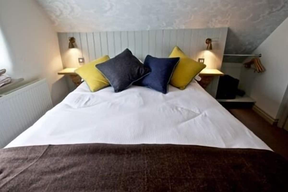 Un dormitorio con cama, almohadas y lámparas de noche.