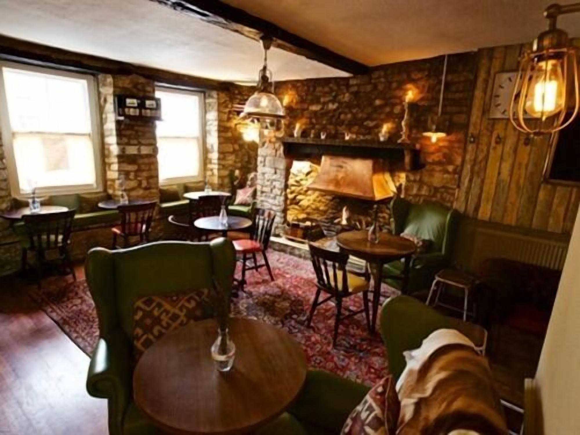 A cozy interior with stone walls, wooden furniture, and a fireplace.