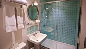 Une salle de bain avec une douche à parois de verre, un lavabo, un miroir et un porte-serviettes.