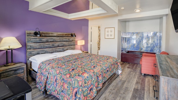 A bedroom with a bed, a nightstand, a dresser, a mirror, and a television. - Hotel O Miami Inn & Suites Chicago Midway Airport (Oak Lawn)