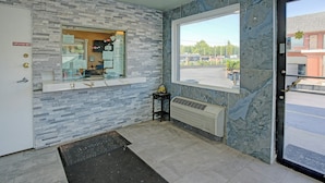 A reception area with a marble wall, a window with a view, a door labeled 'EMPLOYEES ONLY,' and a small table with a plant. - Hotel O Miami Inn & Suites Chicago Midway Airport (Oak Lawn)