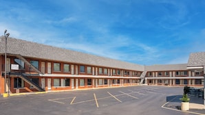 A motel with a parking lot, multiple rooms, and a staircase leading to the entrance. - Hotel O Miami Inn & Suites Chicago Midway Airport (Oak Lawn)
