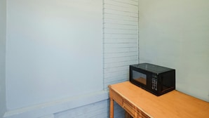 A room with a white wall, a wooden table, and a black microwave on the table. - Hotel O Miami Inn & Suites Chicago Midway Airport (Oak Lawn)